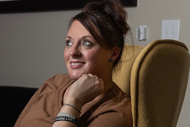 heather morton's headshot taken in her marvel way sober living apartment in reno nevada. heather is wearing a brown shirt, sitting on a brown chair, and has her hand raising to her face, looking thoughtfully in the distance
