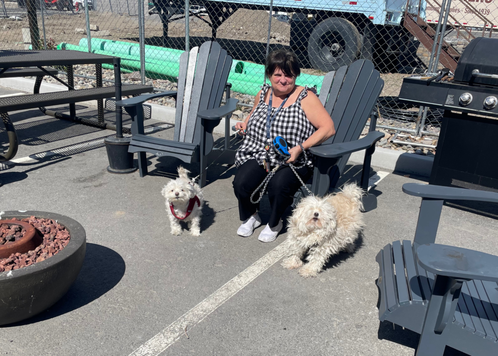 a marvel way resident with her two pet dogs, sitting at a firepit outside the supportive apartment complex
