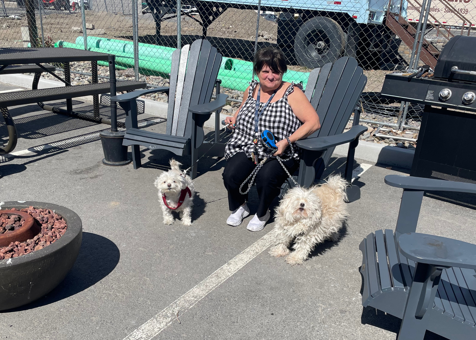 a marvel way resident with her two pet dogs, sitting at a firepit outside the supportive apartment complex