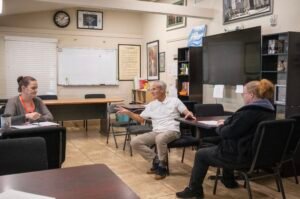 Bill running workforce development programming at the empowerment center's addiction treatment center, bill in center of photo and two female students on sides of photo