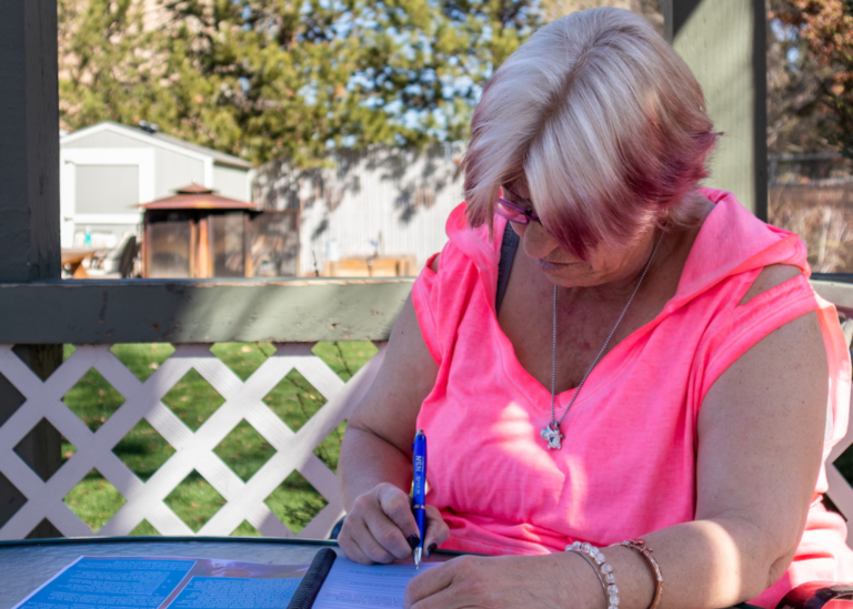woman in pink filling out workforce development workbook at the empowerment center addiction treatment centers garden gazeebo