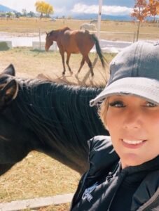 ashley ward with two horses in the background at empowerment center equine therapy