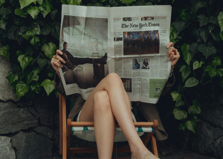 woman sitting in a chair reading about the empowerment center in the newspaper