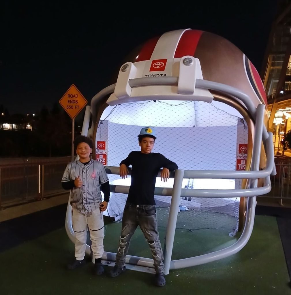 Nicole Hulihee's 2 sons in front of a giant football helmet
