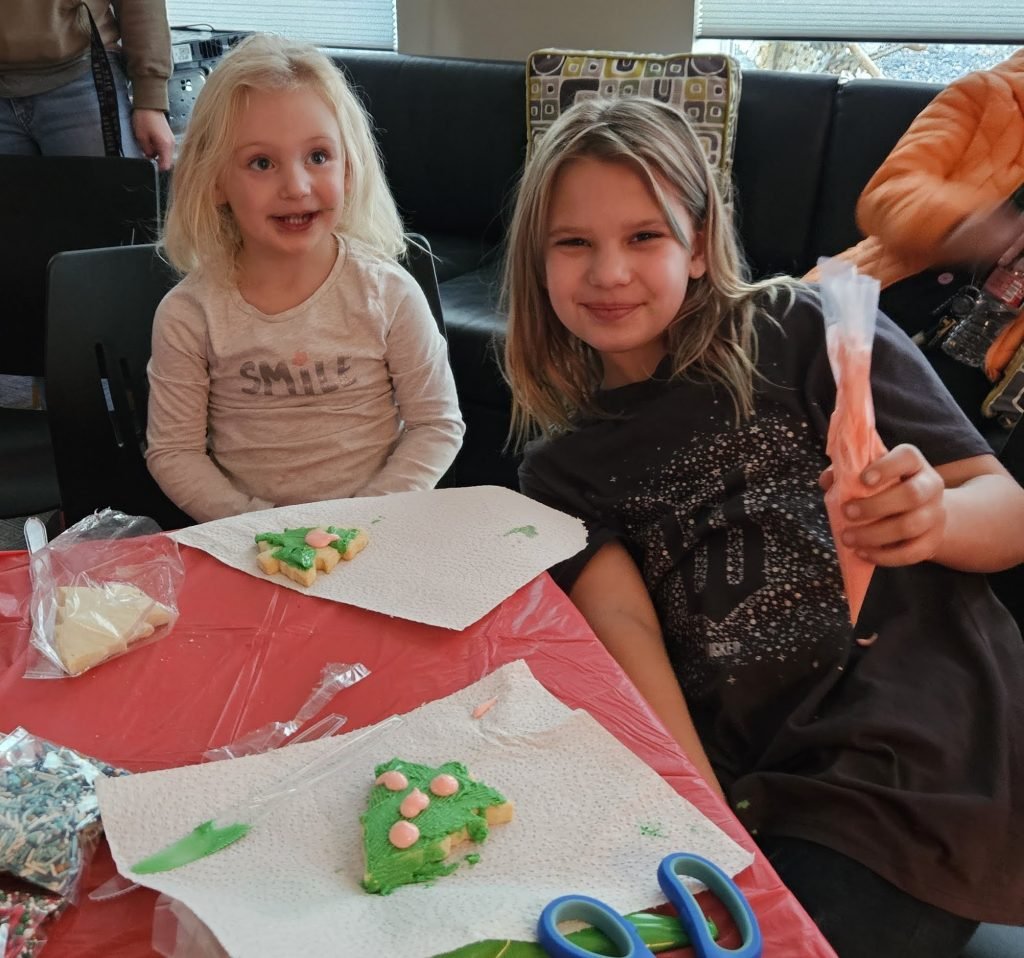 two young girls decorating christmas cookies at marvel way sober living apartments