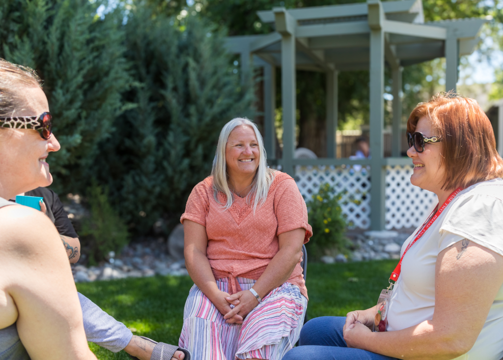 workforce development specialist jessi hall sitting outside the empowerment center speaking with 2 clients in recovery in front of a gazebo