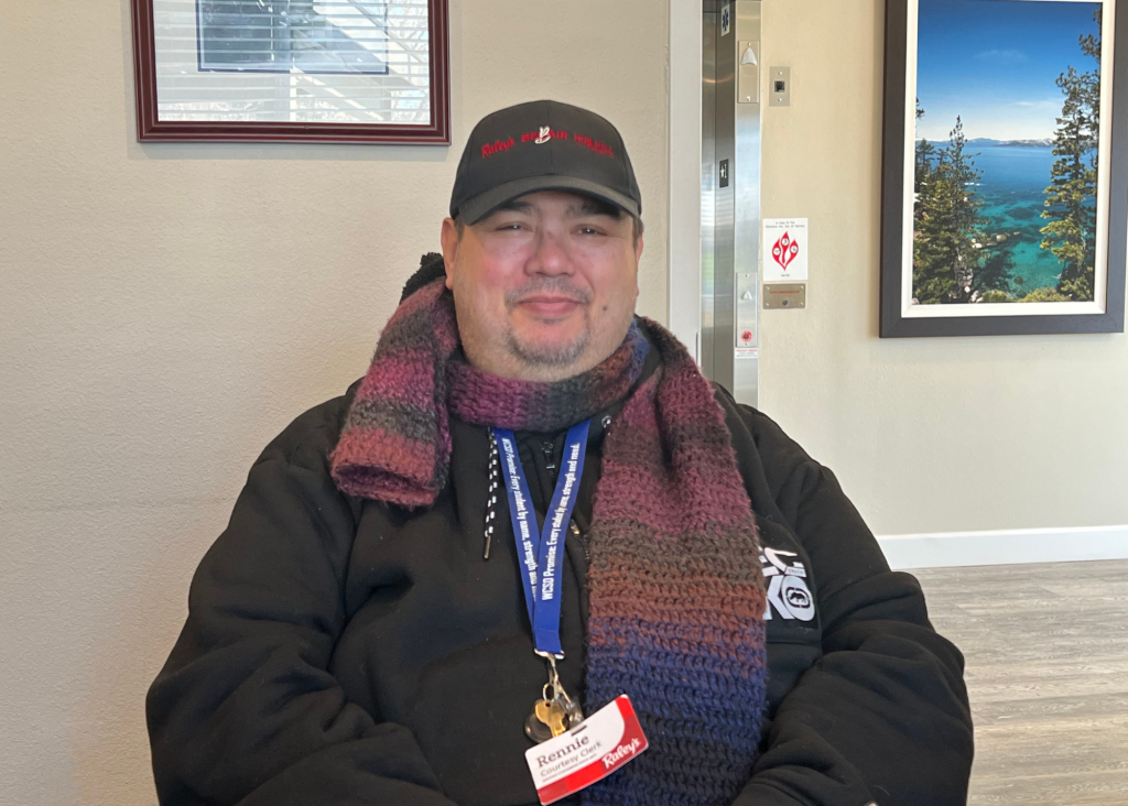 headshot of Rennie Johnson, background is Marvel Way Complex supportive apartemnts in reno nevada, photo of lake tahoe on wall